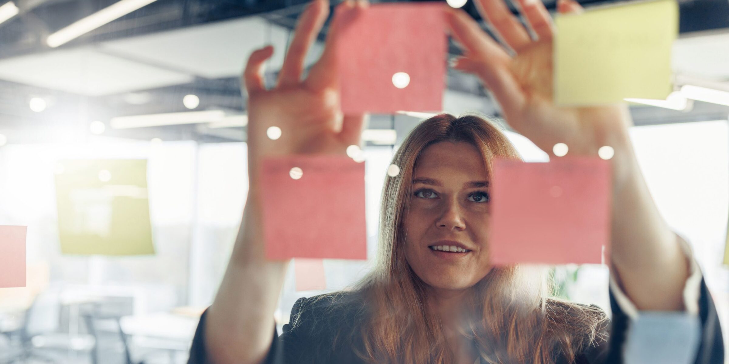 Close up of businesswoman is glues sticky notes on board in modern office