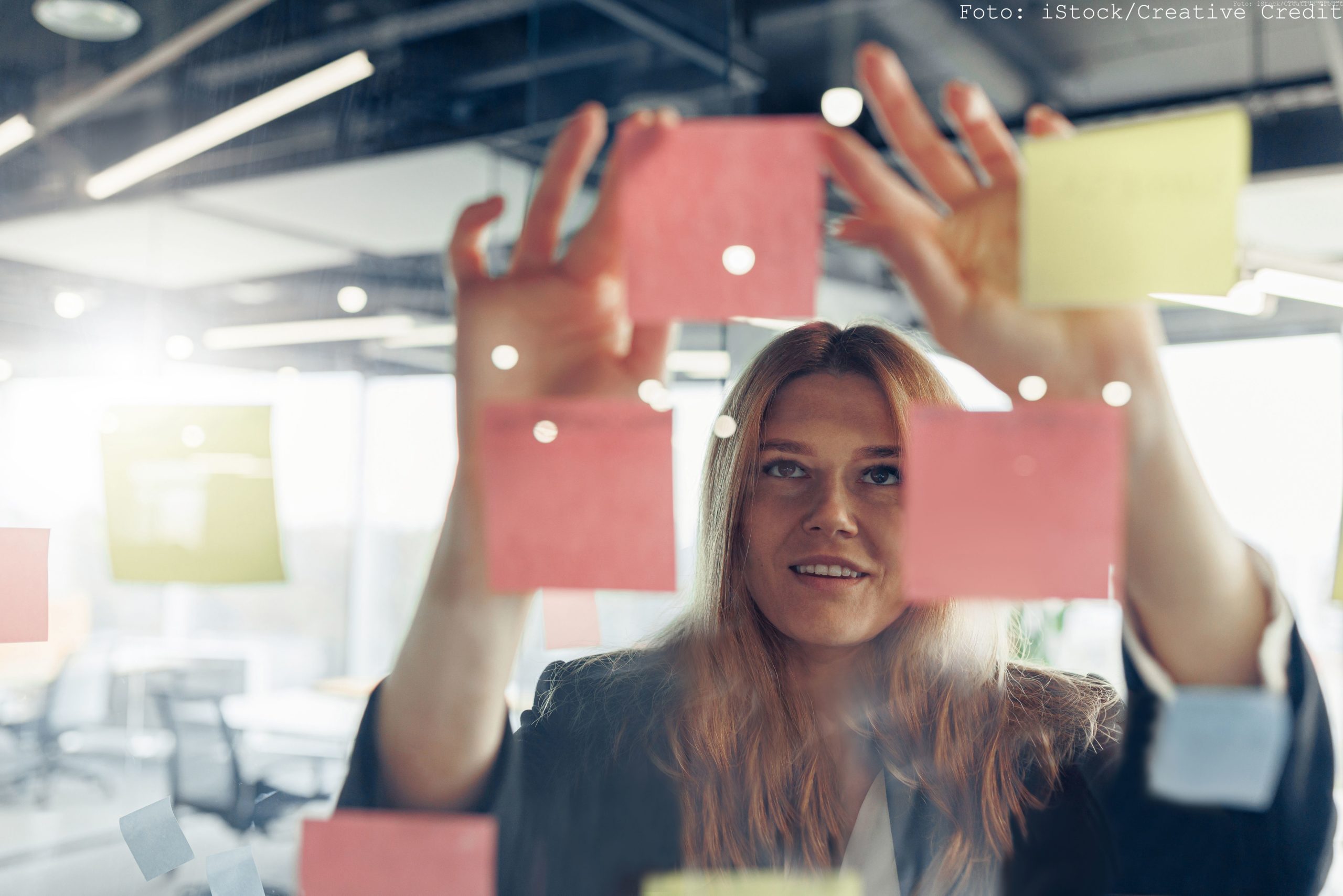 Close up of businesswoman is glues sticky notes on board in modern office